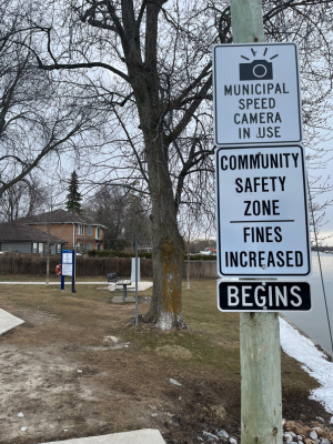 Sign stating Municipal Speed camera in use and a sign stating Community safety zone, fines increased begins 